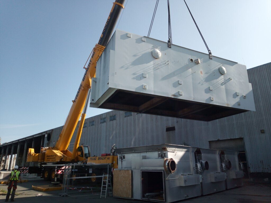 Kran hebt große Abluftreinigungsanlage auf Baustelle